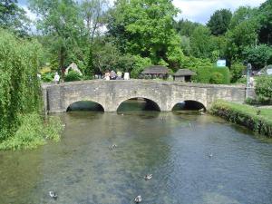a bridge over a river with people walking on it at The Swan Hotel in Bibury