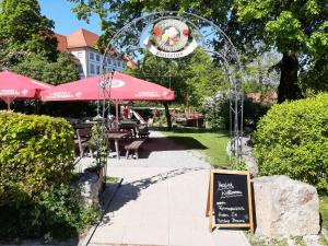 ein Schild in einem Park mit einem Restaurant mit Sonnenschirmen in der Unterkunft Ferienwohnung KIostermühle Irsee - Parkplätze, Spielplatz, Biergarten, Badesee, E-Auto Ladepunkt in Irsee