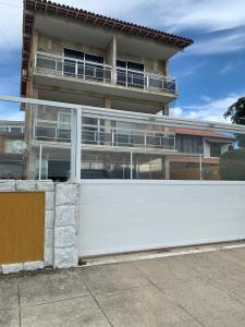 a white fence in front of a building at Casa pôr do sol in São Pedro da Aldeia