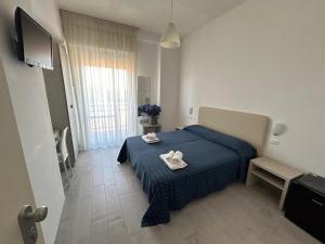 a bedroom with a blue bed with two white shoes on it at Hotel Concorde in Bellaria-Igea Marina