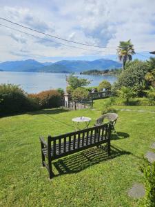 a park bench sitting in the grass next to a table at Villa Maria Lago Maggiore 2 in Leggiuno +17 photos