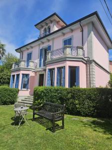 a bench in front of a large pink house at Villa Maria Lago Maggiore 2 in Leggiuno