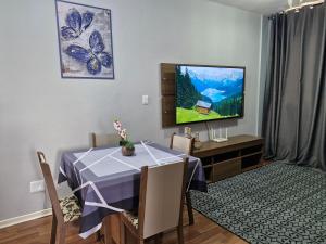 a dining room with a table and a tv at Apto no Centro de São Leopoldo in São Leopoldo