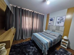 a bedroom with a bed and a television in it at Apto no Centro de São Leopoldo in São Leopoldo