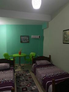 Habitación verde con 2 camas y mesa en Charming Lakeside Stay, en Pogradec