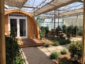 a garden with a wooden porch and a greenhouse at Very unique 'tiny house' with Hottub in Rijsenhout