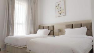 two white beds in a room with a window at Excellent 2br Stay In Yas Island in Abu Dhabi +13 photos