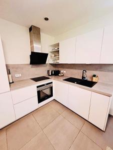 a kitchen with white cabinets and a sink at Beautiful Flat with garden view, terrace and parking-105 in Luxembourg