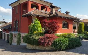 a red house with bushes in front of it at VILLA LAURA Rooms & Pool in Fossano