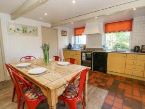 cocina con mesa de madera y sillas rojas en The Stone Masons House, en Keighley