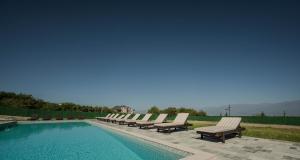 a row of lounge chairs next to a swimming pool at TITA HOMES in Telavi