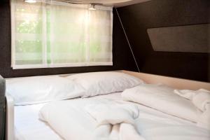 un letto con cuscini bianchi in una stanza con finestra di Bauer Caravan in FKK Camping Solaris a Poreč (Parenzo)