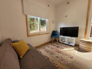 a living room with a couch and a flat screen tv at Cabaña del Chucao in Valdivia