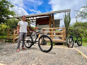 a man is standing next to a bike at Bosque Seco Bioreserva & Hostel in Villavieja