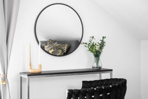 a mirror on a table with a black chair at Luksusowy Apartament Pod Lasem Szczecin-Pilchowo in Pilchowo