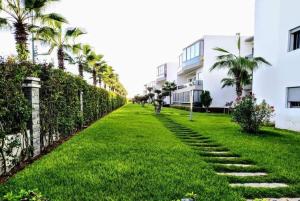 a grassy yard with palm trees and a fence at La perle de blanca beach in Sidi Rahal