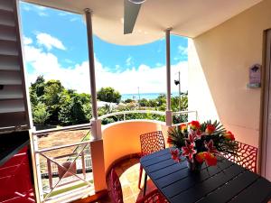 a table with a vase of flowers on a balcony at Studio ROUGE GORGE TARTANE in La Trinité
