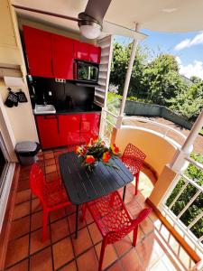 a kitchen with red cabinets and a table and chairs at Studio ROUGE GORGE TARTANE in La Trinité