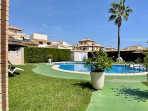 a swimming pool in a yard with a palm tree at Terraced Home in Cabo Roig in Cabo Roig