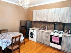 a kitchen with a table and a stove and a refrigerator at Kamara Apartment in Kazbegi