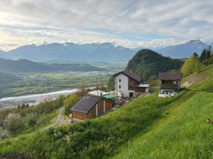 a green hill with houses on a hill with a river at Agriturismo Saettà in Lentiai