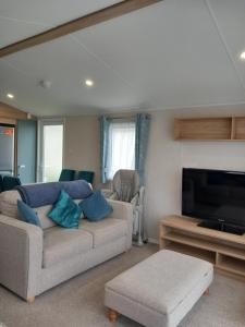 a living room with a couch and a flat screen tv at Walnut 65 - Porthcawl in Newton
