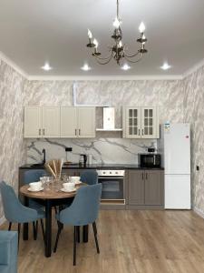 a kitchen with a table and chairs and a refrigerator at Athletic city in Taldykolʼ