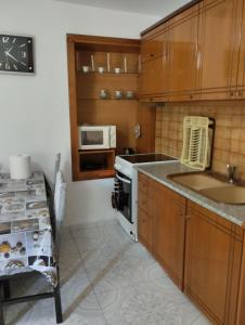 Una cocina con armarios de madera, fregadero y microondas. en Seaside Break Apartment, en Sarandë