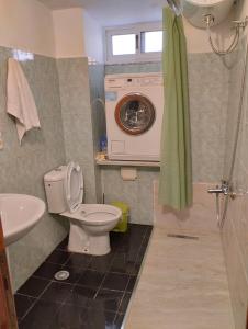 Un baño con inodoro y lavadora. en Seaside Break Apartment, en Sarandë