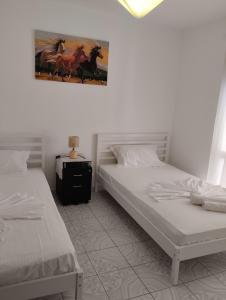Un dormitorio con dos camas y un cuadro en la pared. en Seaside Break Apartment, en Sarandë