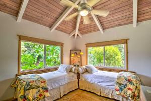 two beds in a room with two windows at Kauai Hale Melemele by Coldwell Banker Island Vacations in Kapaa
