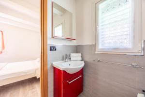 baño con armario rojo y lavamanos en Villetta ai Pini by Venicevillas, en Cavallino-Treporti