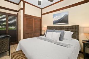 a bedroom with a large bed with white sheets and pillows at Kauai Kiahuna Plantation #104 by Coldwell Banker Island Vacations in Kipu +14 photos