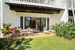 a patio with a table and chairs in a yard at Kauai Kiahuna Plantation #104 by Coldwell Banker Island Vacations in Kipu