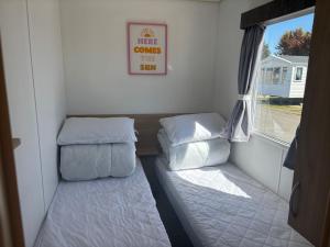 a small room with two beds and a window at Robin Hood 3-Bed Caravan Sleeps 8 Pet Friendly in Rhyl