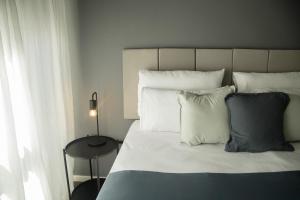 1 dormitorio con cama con almohadas blancas y mesa en El Misti Suites Buenos Aires, en Buenos Aires