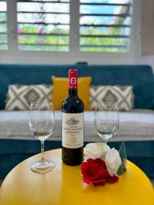 a bottle of wine sitting on a table with two glasses at La Ruche de Maïa - Piscine - Jardin - Plage à 100m in Grand-Bourg