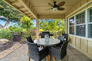 a patio with a table and chairs and a ceiling fan at Kauai Wainani Villa by Coldwell Banker Island Vacations in Koloa