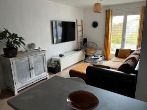 a living room with a couch and a flat screen tv at Villa Riva-Mela in Ouistreham