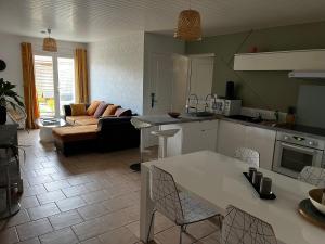 a kitchen and living room with a table and a couch at Villa Riva-Mela in Ouistreham
