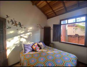 a bedroom with a bed and a window at Casinha das bananeiras in Delfinópolis