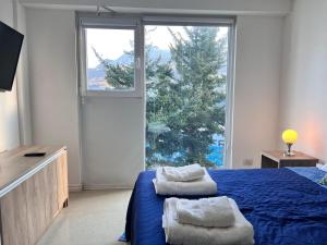 une chambre avec un lit bleu et une grande fenêtre dans l'établissement Gray Fox Apartments - Martial, à Ushuaia 5 autres photos