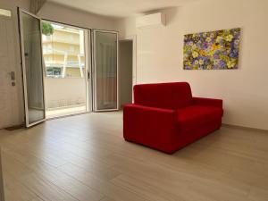 a red chair in a room with a painting on the wall at Le Casine di Cervia in Cervia