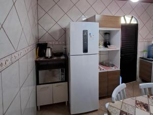 a white refrigerator in a small kitchen with a table at Casinha do Trapiche in Penha