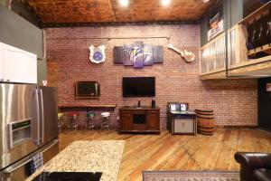a room with a brick wall with a tv and a kitchen at The Law Suites in Nashville