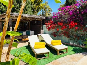 a patio with two chairs and a table and flowers at Gothia Villa Exclusiva Villa con Piscina Sauna in Illes Balears