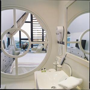 La salle de bains est pourvue d'un miroir rond et d'un lavabo. dans l'établissement Hostellerie de la Pointe Saint-Mathieu - SPA & Restaurant, à Plougonvelin