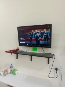 a flat screen tv on a shelf on a wall at Roomstay Floral in Sri Gading