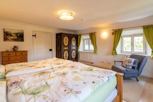 a bedroom with a bed and a chair and windows at Huberhof Meisham in Eggstätt