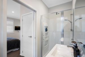 a white bathroom with a shower and a sink at Kaitahi Lodge in Palmerston North